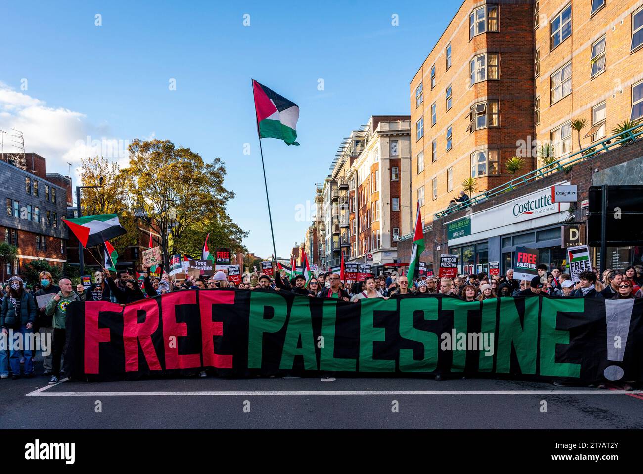 Die Menschen marschieren durch London mit Einem Banner für das freie Palästina, das zu Einer Waffenruhe im Gazastreifen während des Marsch für Palästina-Events in London, Großbritannien, aufruft Stockfoto