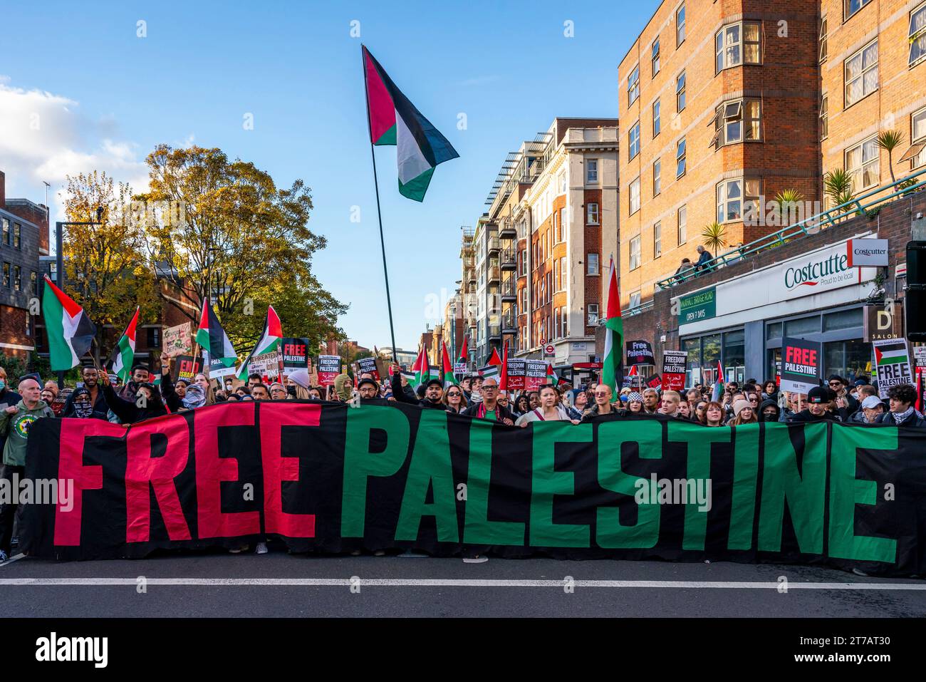 Die Menschen marschieren durch London mit Einem Banner für das freie Palästina, das zu Einer Waffenruhe im Gazastreifen während des Marsch für Palästina-Events in London, Großbritannien, aufruft Stockfoto