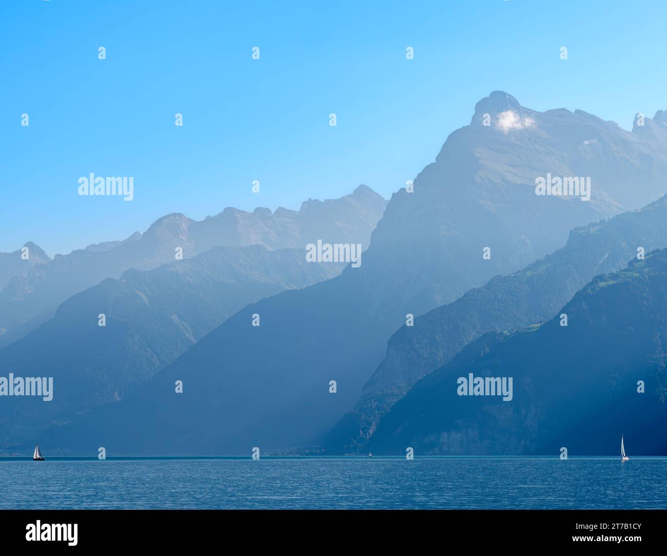 Umrisse der Berge am schweizer Urnersee im tagsüber trüben Licht. Segelboote auf dem See Stockfoto