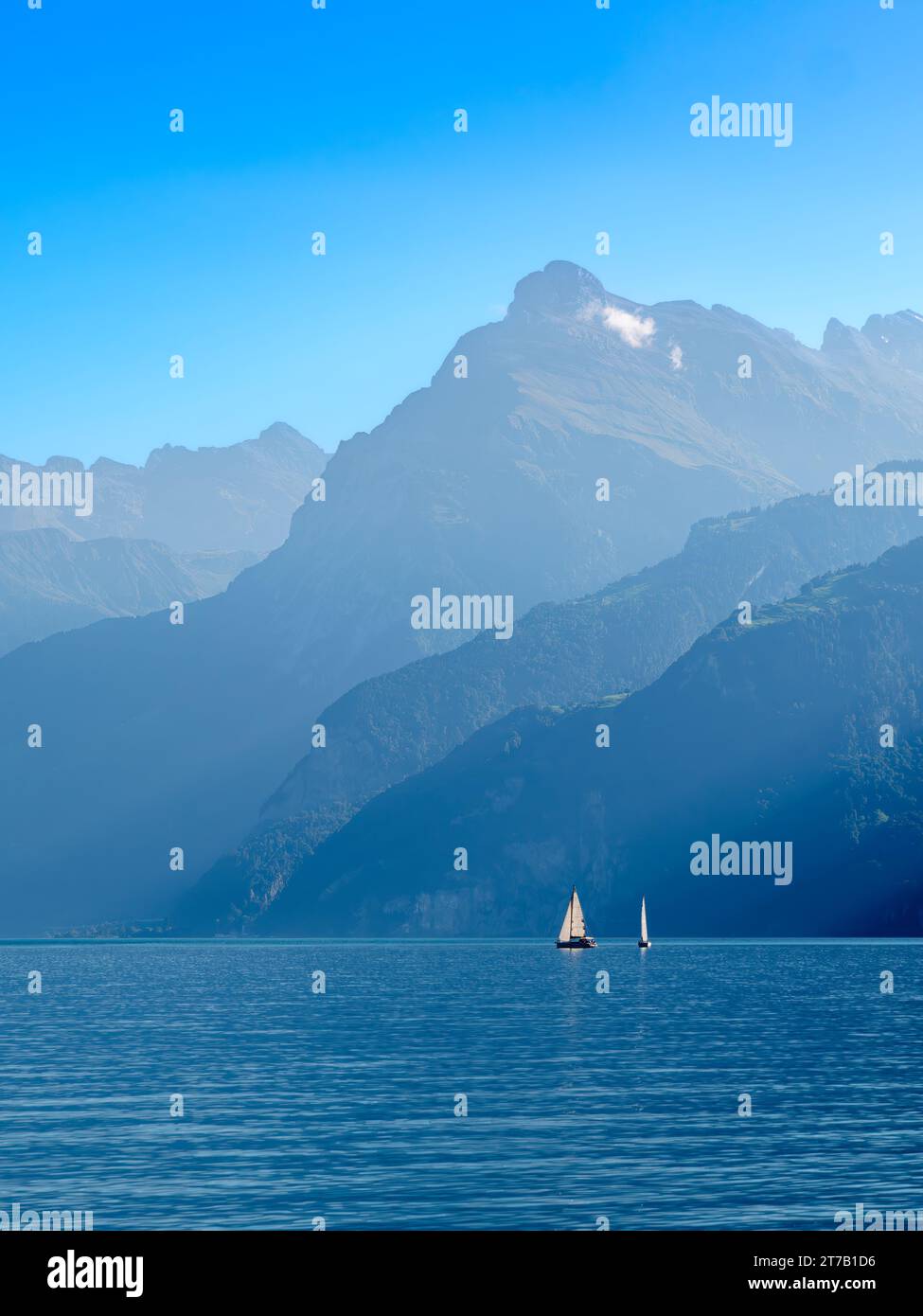Umrisse der Berge am schweizer Urnersee im tagsüber trüben Licht. Segelboote auf dem See Stockfoto