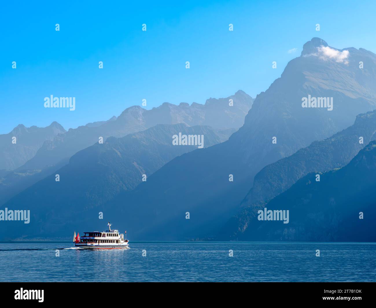Umrisse der Berge am schweizer Urnersee im tagsüber trüben Licht. Touristenschiff auf dem See. Stockfoto