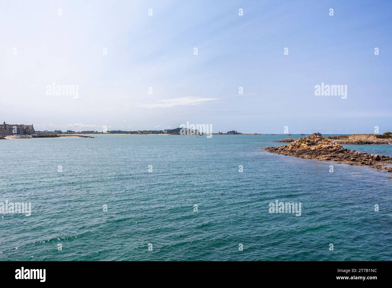 Halbzeitgestein entblößt vor dem Alten Hafen von Roscoff, mit der Presqu'île de Perharidy in der Ferne: Finistère, Bretagne, Frankreich Stockfoto