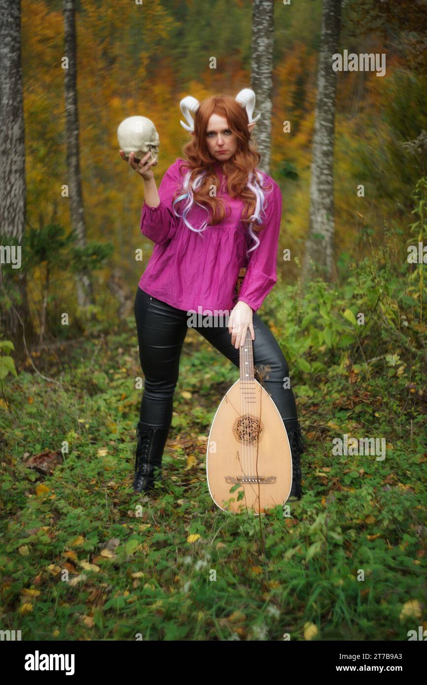 Intensives Ganzkörper-Porträt einer weiblichen Tiefling von Dungeons & Dragons, die Augen mit der Kamera schließt. Ein leicht bösartiges Leuchten in ihrem ernsthaften Blick als Stockfoto