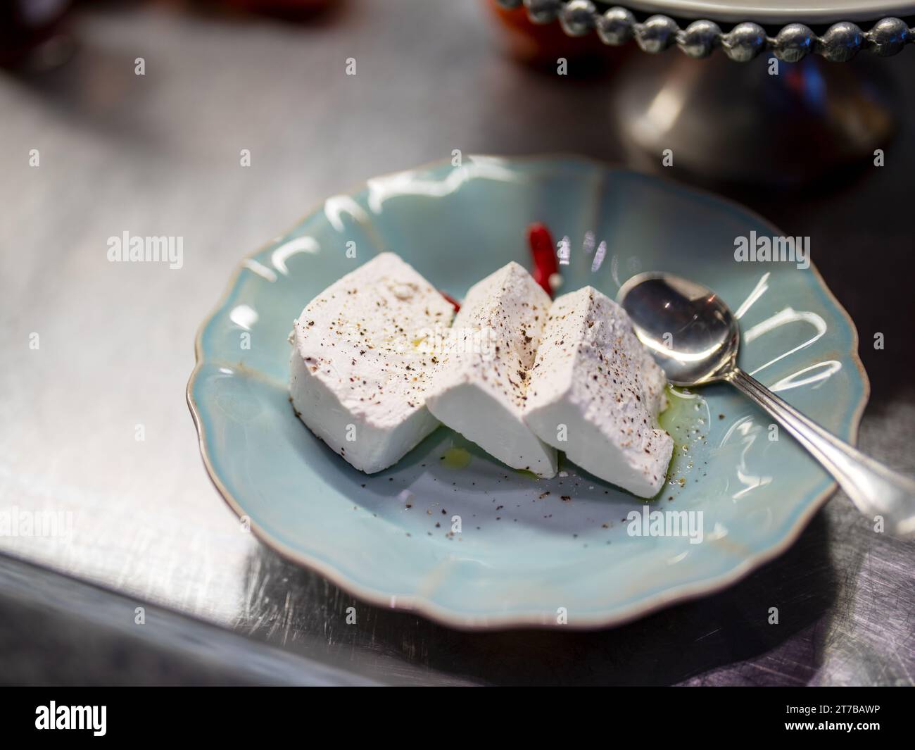 Farbbild eines türkisfarbenen Serviertellers mit Fetakäse auf einer Salatbar. Stockfoto