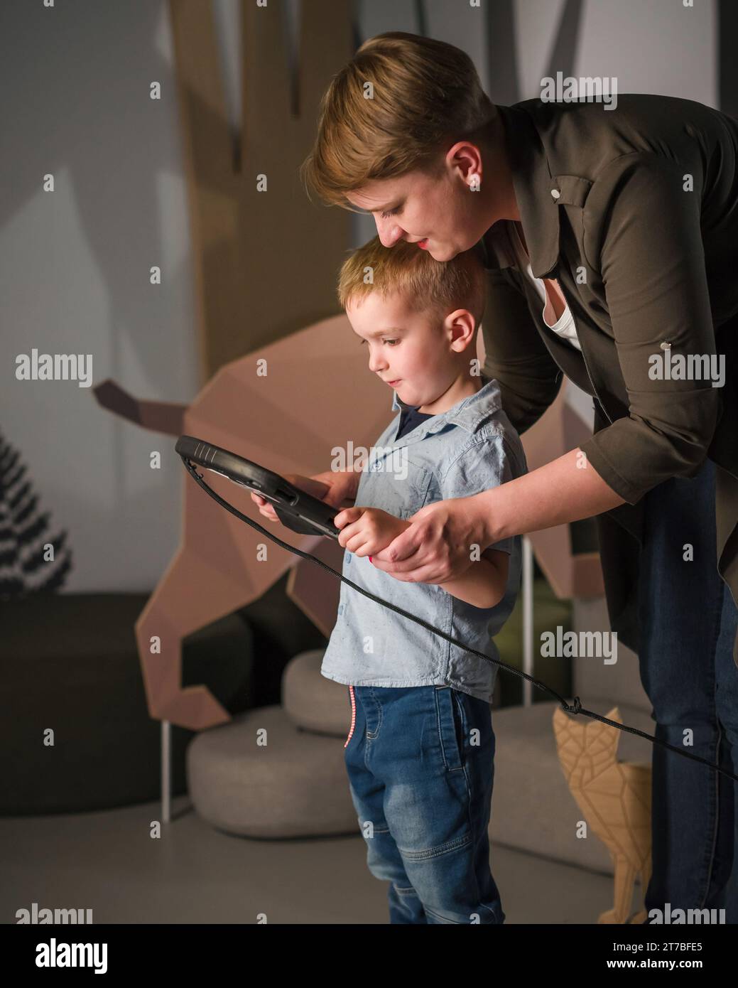 Junge mit Touchscreen-Tablet-Display in einem Museum mit seiner Mutter. Kinder und moderne Technikkonzepte. Stockfoto