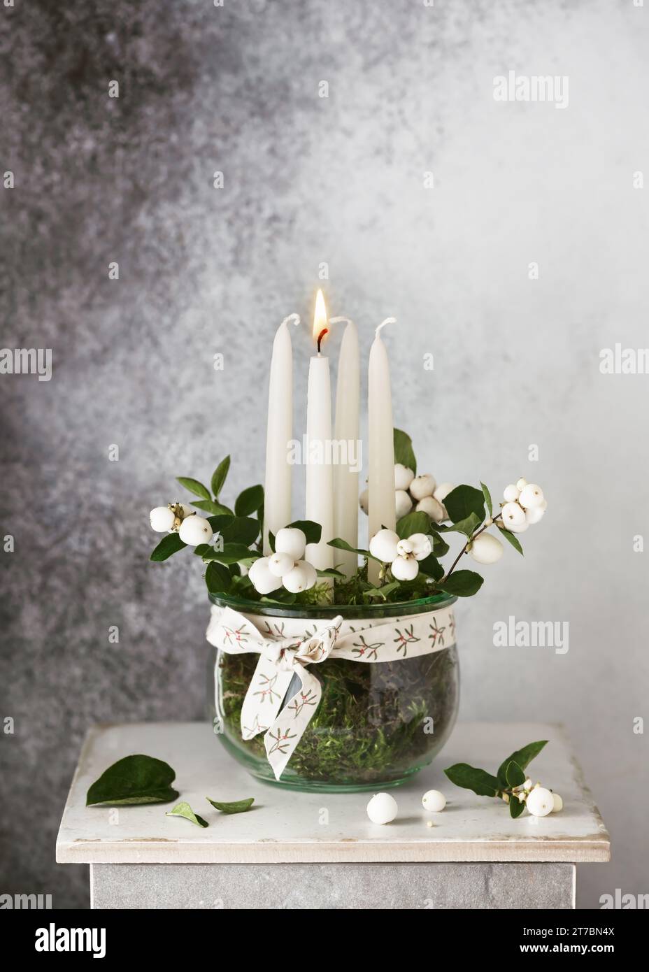 1. Advent. Weihnachtsdekoration mit weißen Adventskerzen und Schneebeerzweigen im Glasgefäß. Handgefertigte Wohndekoration. Stockfoto