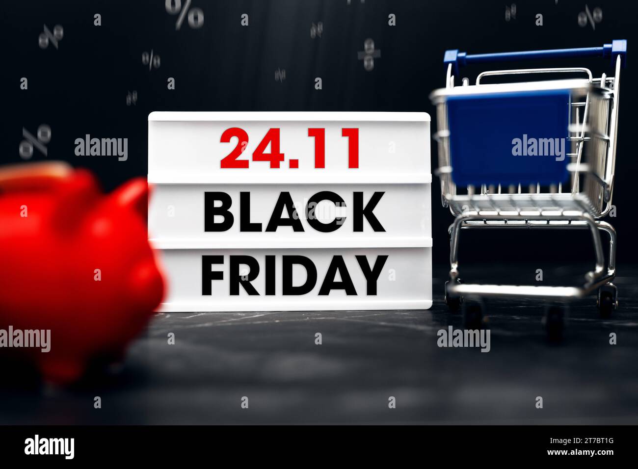 Augsburg, Bayern, Deutschland - 13. November 2023: 24,11 Black Friday-Schriftzug auf einem Leuchtkasten neben einem Einkaufswagen und einer roten Schweinebank. Angebote für die Black Friday Sales Event Concept FOTOMONTAGE *** 24,11 Black Friday Schriftzug auf einer Lightbox neben einem Einkaufswagen und einem roten Sparschwein. Angebote zum Black-Friday Verkaufsevent Konzept FOTOMONTAGE Credit: Imago/Alamy Live News Stockfoto