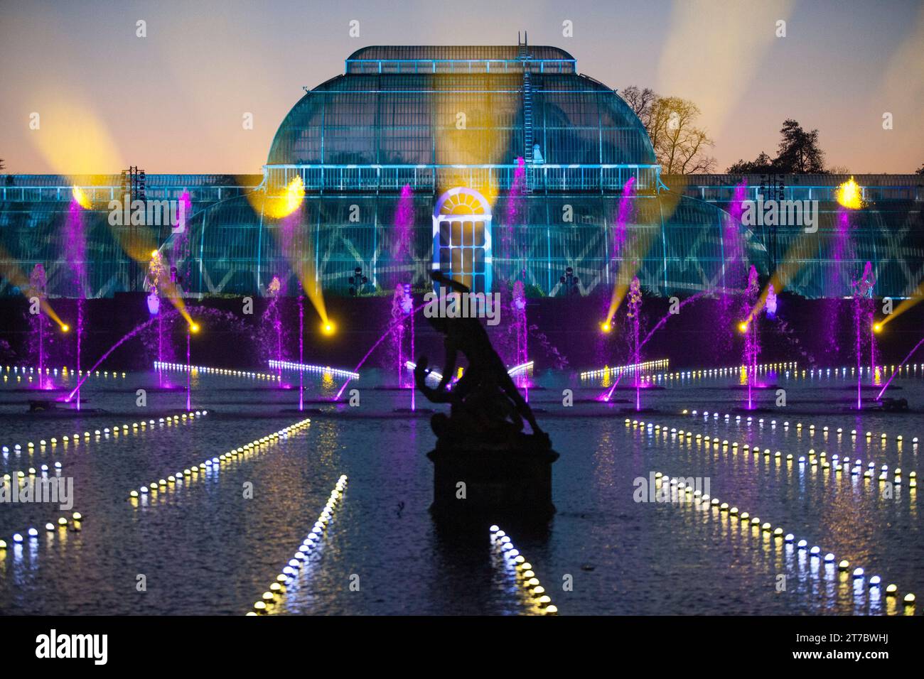 London, Großbritannien. November 2023. Die Weihnachtsfeier im Kew Lights sind vom 15. November bis zum 7. Januar 2024 für die Öffentlichkeit bereit. Mit 21 verschiedenen Lichtinstallationen sowie Stopps für Speisen und Getränke, ist das große Finale die Weihnachtssinfonie mit Musik, Lichtern und Springbrunnen, die von der anderen Seite des Teichs aus mit dem Palmenhaus als Kulisse betrachtet werden. Quelle: Anna Watson/Alamy Live News Stockfoto