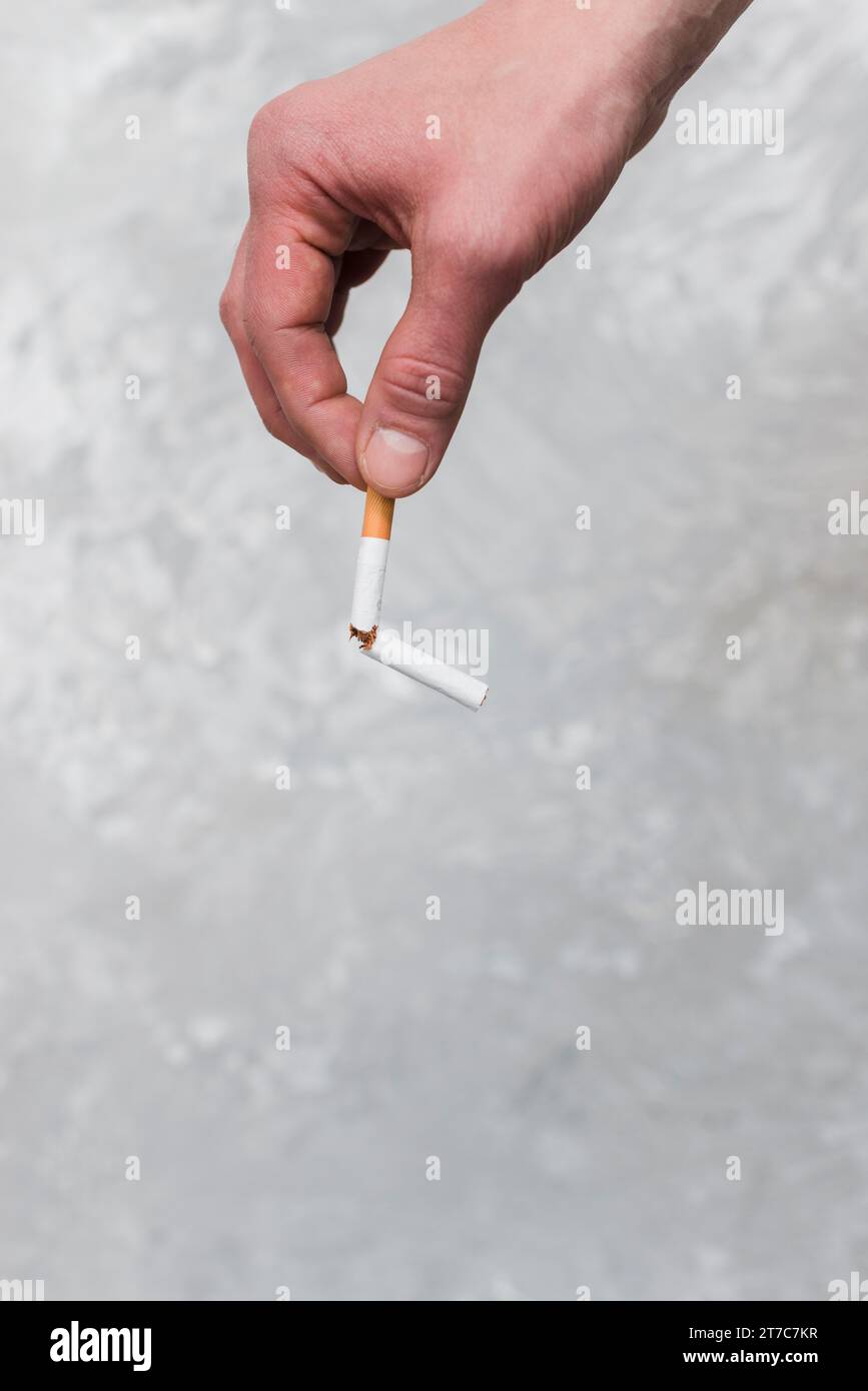 Personen Hand hält kaputte Zigarette alten Wandhintergrund Stockfoto