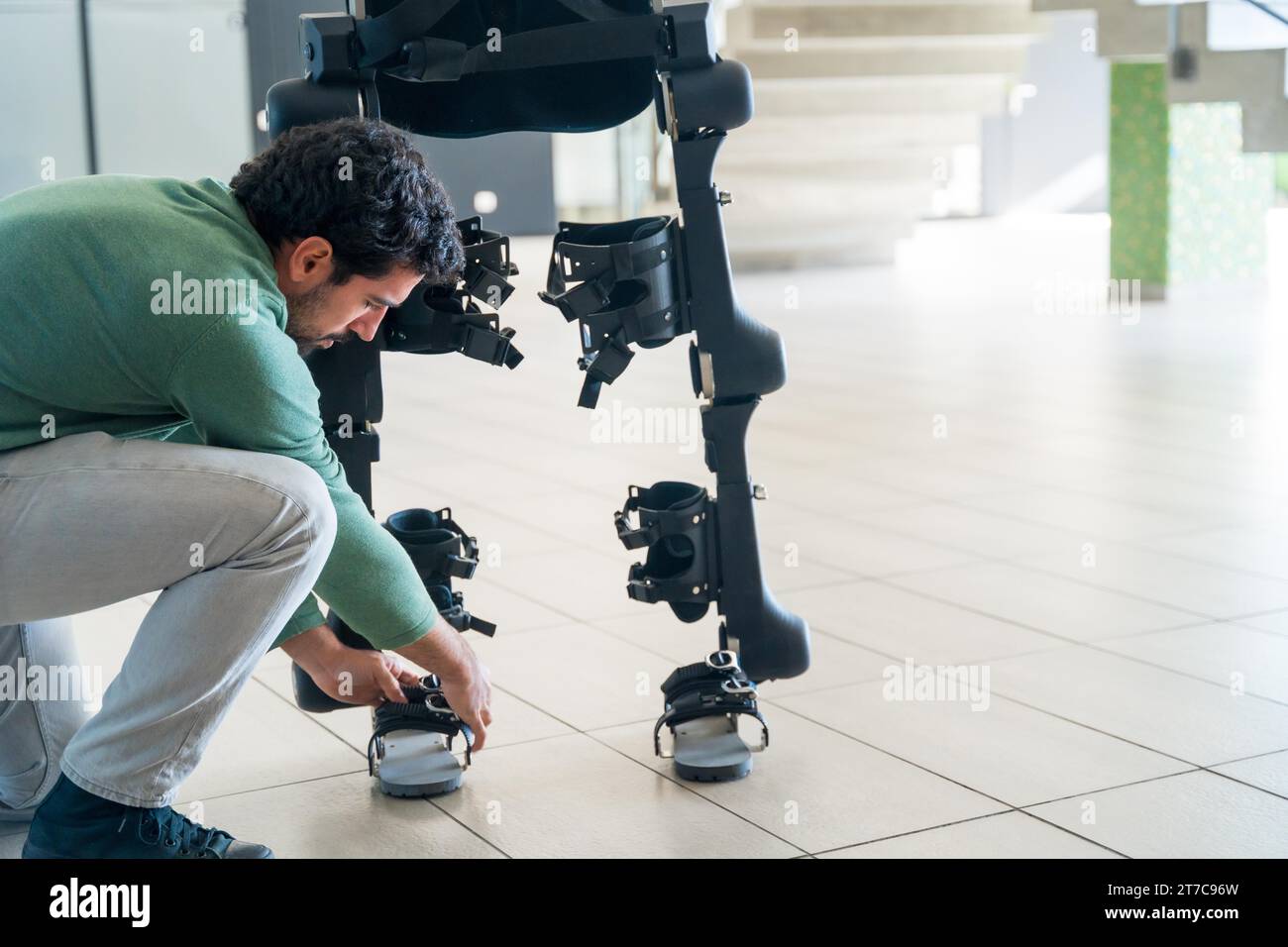 Mechanischer Exoskelett-Ingenieur, der den Roboter vor der Auslieferung an den Kunden überprüft. Physiotherapie in einem modernen Krankenhaus: Roboterskelett. Physiotherapie Stockfoto