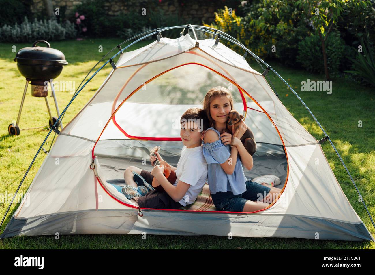 Kleine Schwester genießt Picknick, während sie im Zelt sitzt Stockfoto