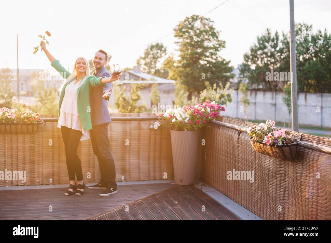 Porträt glückliches Paar mit Weinglas-Rose posiert Balkon Stockfoto