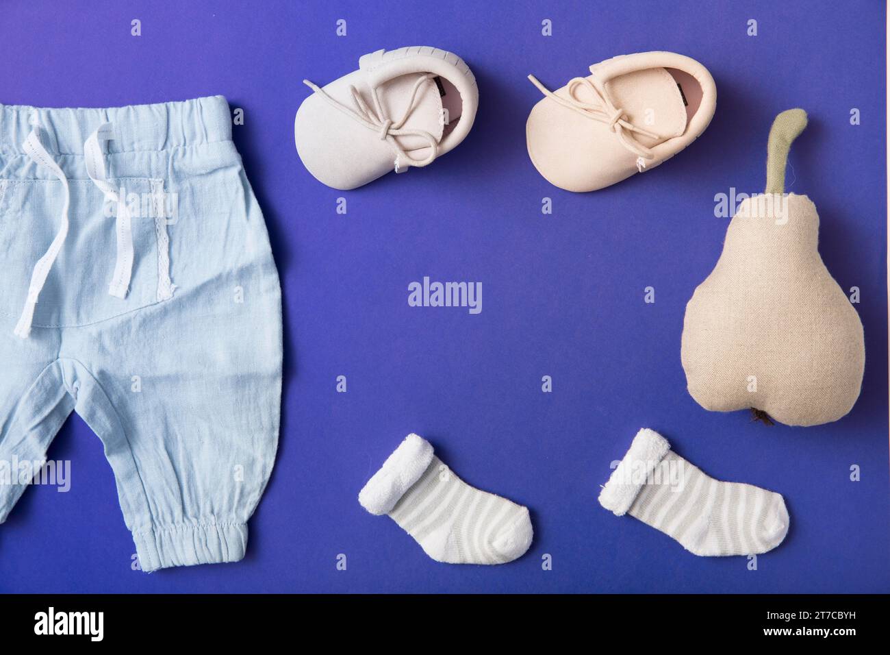 Rosa Babyschuhe Socke Babyhose mit gefüllten Birnen hellblauem Hintergrund Stockfoto