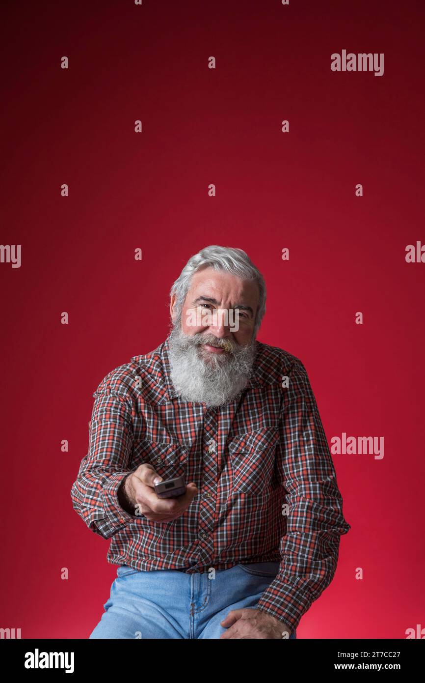Portrait lächelnder Seniorenmann wechselt den Kanal mit Fernbedienung Stockfoto