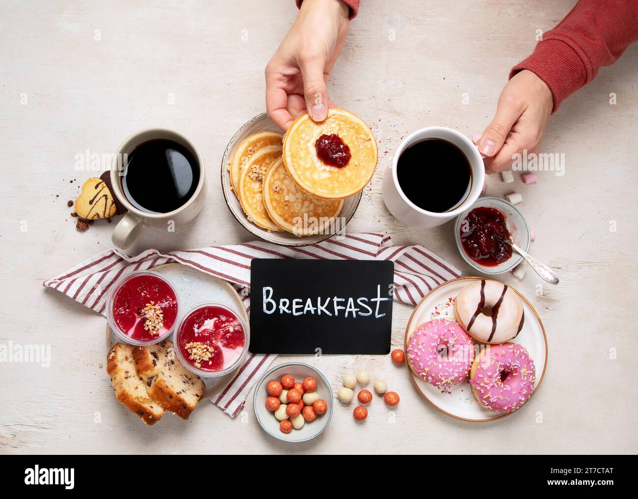 Tisch mit verschiedenen amerikanischen Keksen, Donuts, Pfannkuchen und Kaffeetassen auf weißem Hintergrund. Draufsicht. Stockfoto
