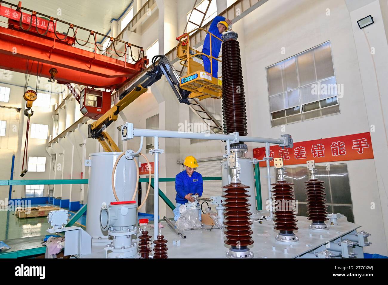 QINGZHOU, CHINA - 15. NOVEMBER 2023 - Arbeiter bauen große Energiespartransformatoren in einem Elektrogerätehersteller in Qingzho zusammen Stockfoto