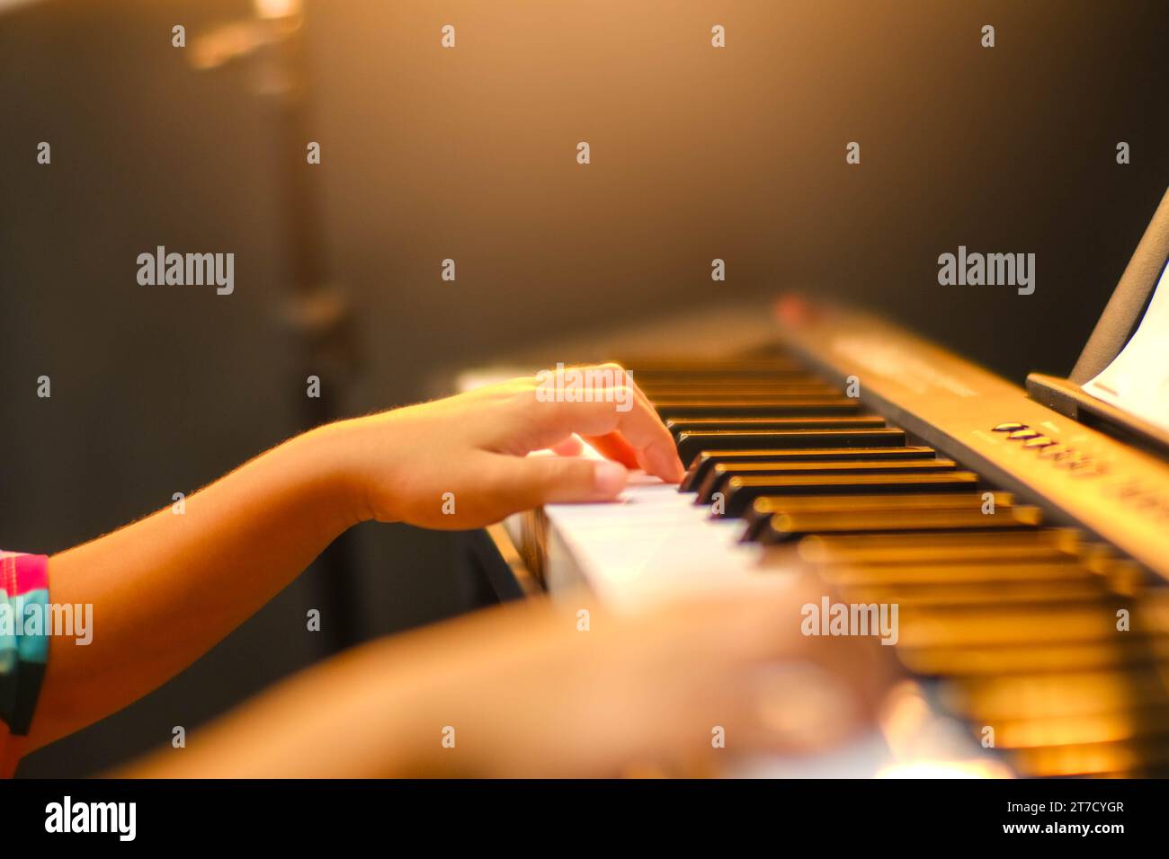 Nahaufnahme der Hand eines kleinen Schülers, der Klavier spielt. Glückliches junges asiatisches Mädchen, das Klavier lernt und übt. Selektiver Fokus. Stockfoto