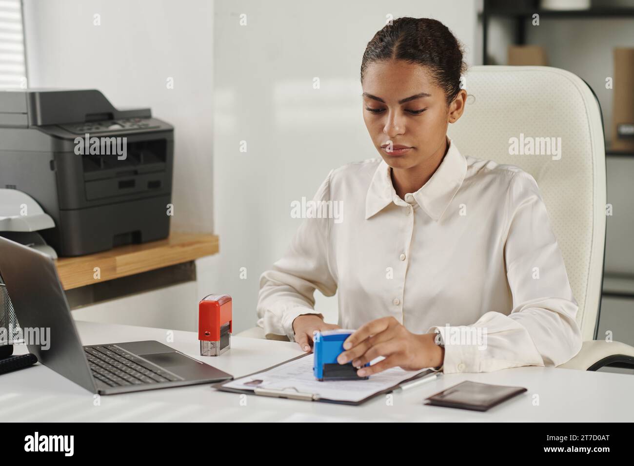 Spezialist, der Dokumente für die Visumgenehmigung im Visumzentrum abstempelt Stockfoto