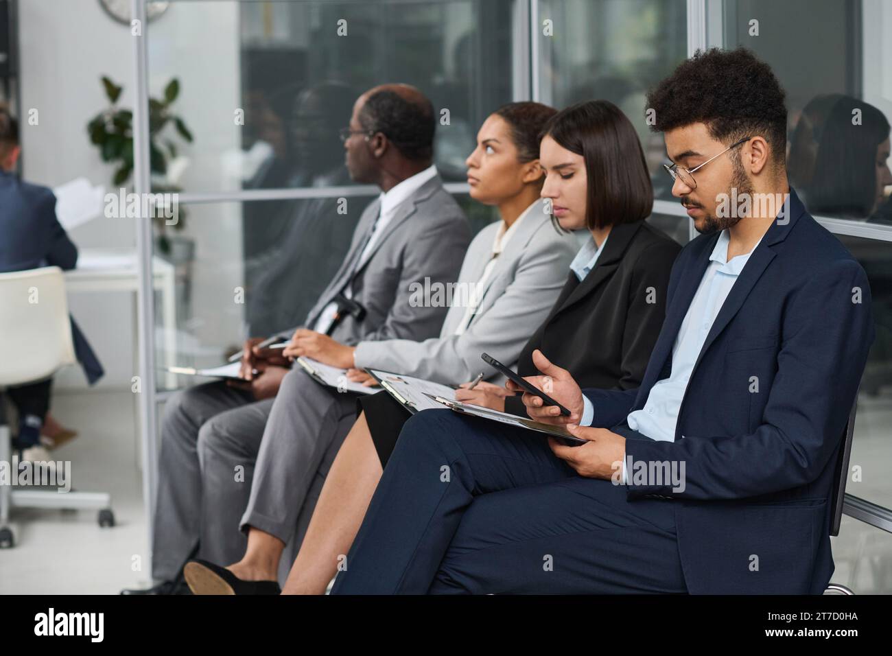 Personen mit Dokumenten, die in der Schlange im Visumzentrum warten, um ein Visum zu bekommen Stockfoto