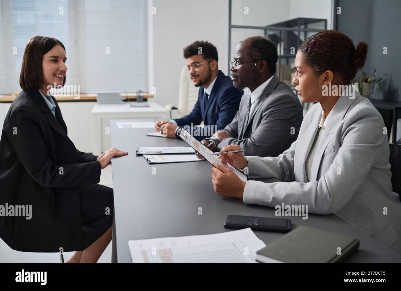 Junge Frau, die ein Interview mit Spezialisten des Visumzentrums hat, um ein Visum zu bekommen Stockfoto