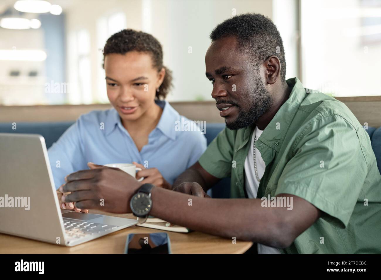 Junge Kollegen, die während der Besprechung im Café gemeinsam am Laptop arbeiten Stockfoto