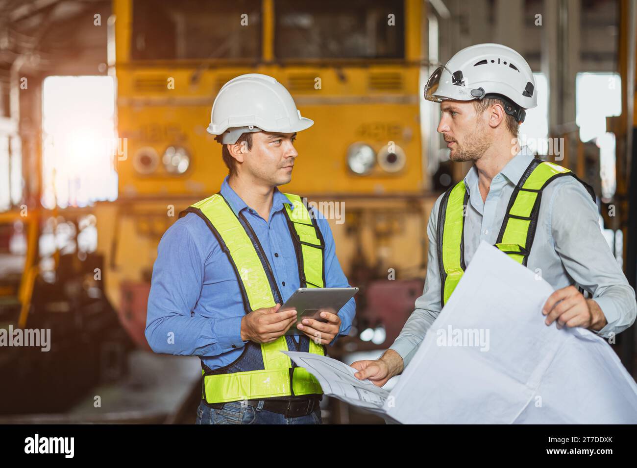 Ingenieur-Team intelligenter junger Facharbeiter beratender Supervisor, der zusammen mit dem Entwurf des Grundrisses in der Werkstatt des Bahnhofs für Lokomotiven arbeitet Stockfoto