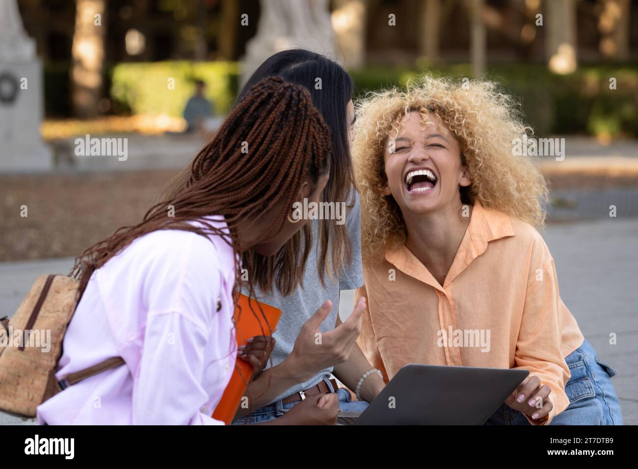 Drei multiethnische Studenten, die nach dem Universitätsunterricht zusammen gelacht haben, lachen mit positiver Stimmung auf dem Campus Stockfoto