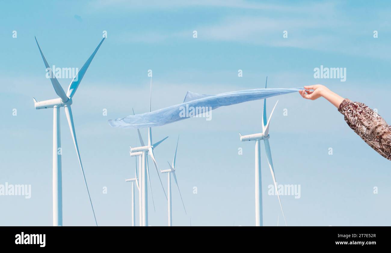 Frauenhände genießen die Brise in der Windenergieanlage und eine Windkraftanlage dahinter Stockfoto