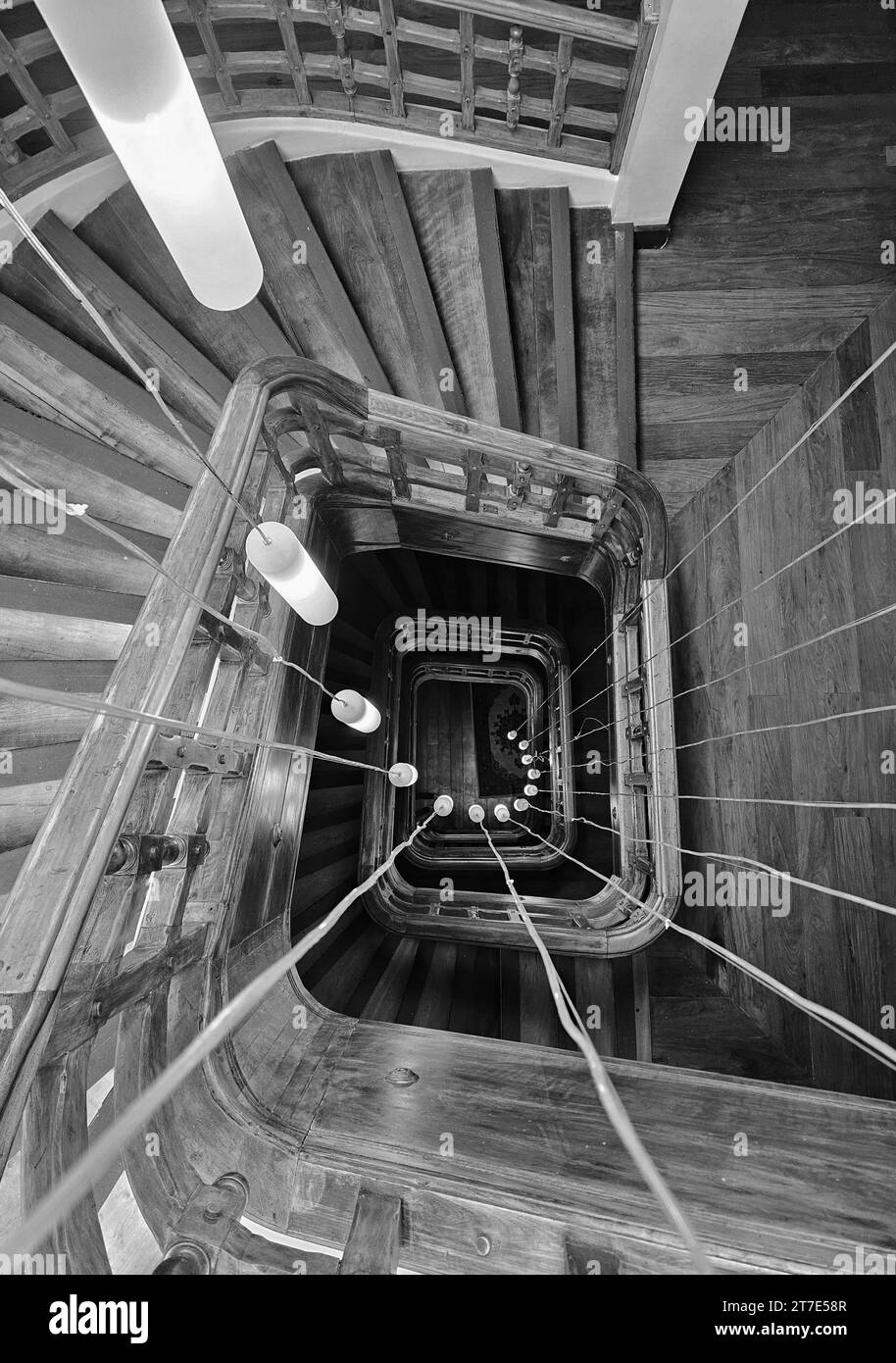 Ein ästhetisch ansprechendes Schwarz-weiß-Foto einer robusten und robusten Treppe, verziert mit starken, geflochtenen Seilen, die von oben verlaufen Stockfoto