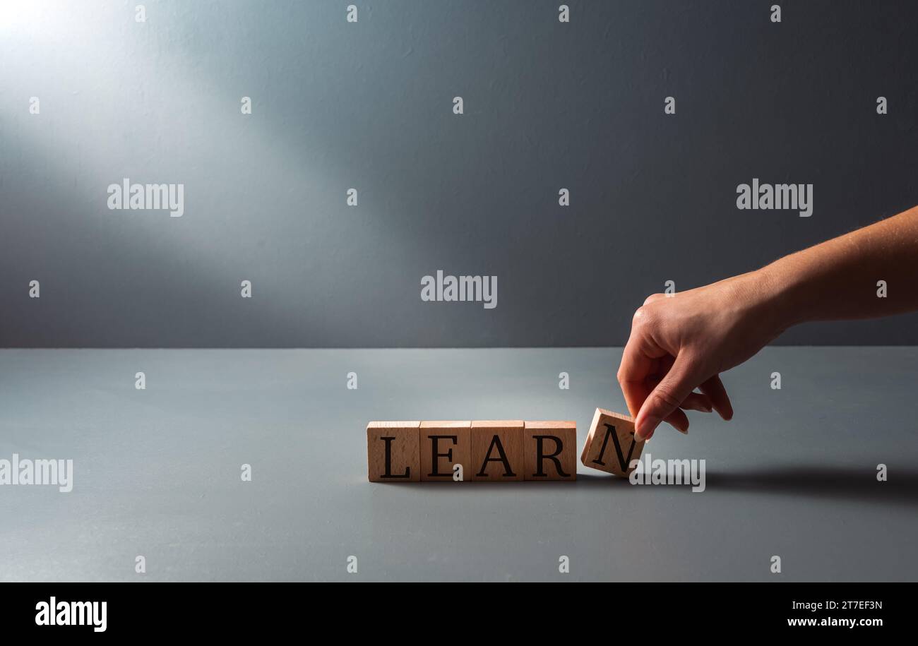 Holzblöcke mit dem Wort Learn , Konzept des Lehnens , Erwachsenenbildung , auf blaugrauem Hintergrund mit Kopierraum . Stockfoto