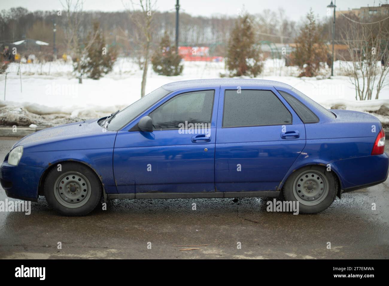 Blaues Auto im Winter. Russisches Auto auf dem Parkplatz. Blauer Transport mit getönten Fenstern. Auto auf Schnee. Stockfoto