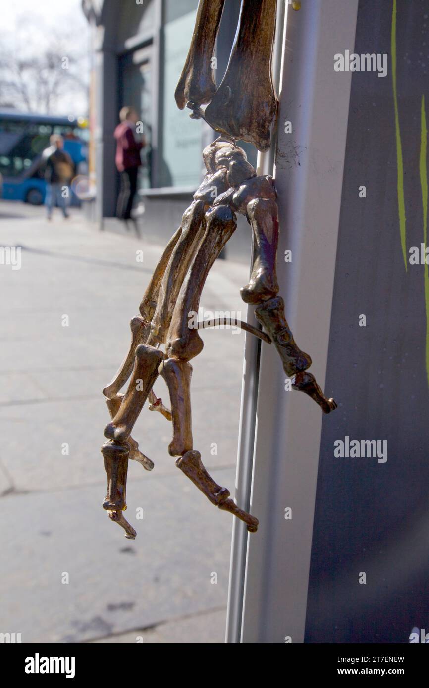 Nahaufnahme einer knochigen Skeletthand mit Leuten auf der Straße im Hintergrund. Stockfoto