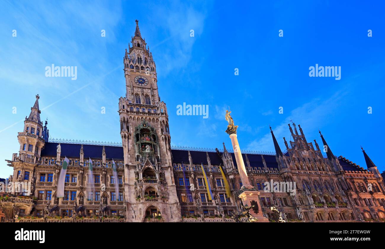 Blick auf das Rathaus mit Uhrenturm auf dem Marienplatz, beleuchtet bei Dämmerung in München, Deutschland Stockfoto