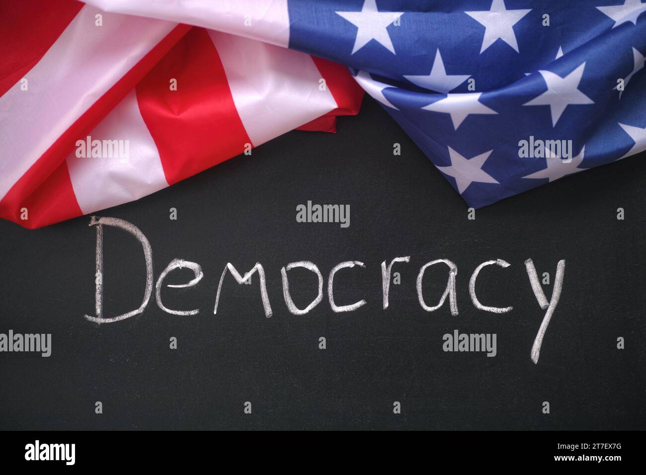 Die Flagge der USA, die auf einer Tafel liegt, auf der das Wort Demokratie steht. Nahaufnahme. Stockfoto