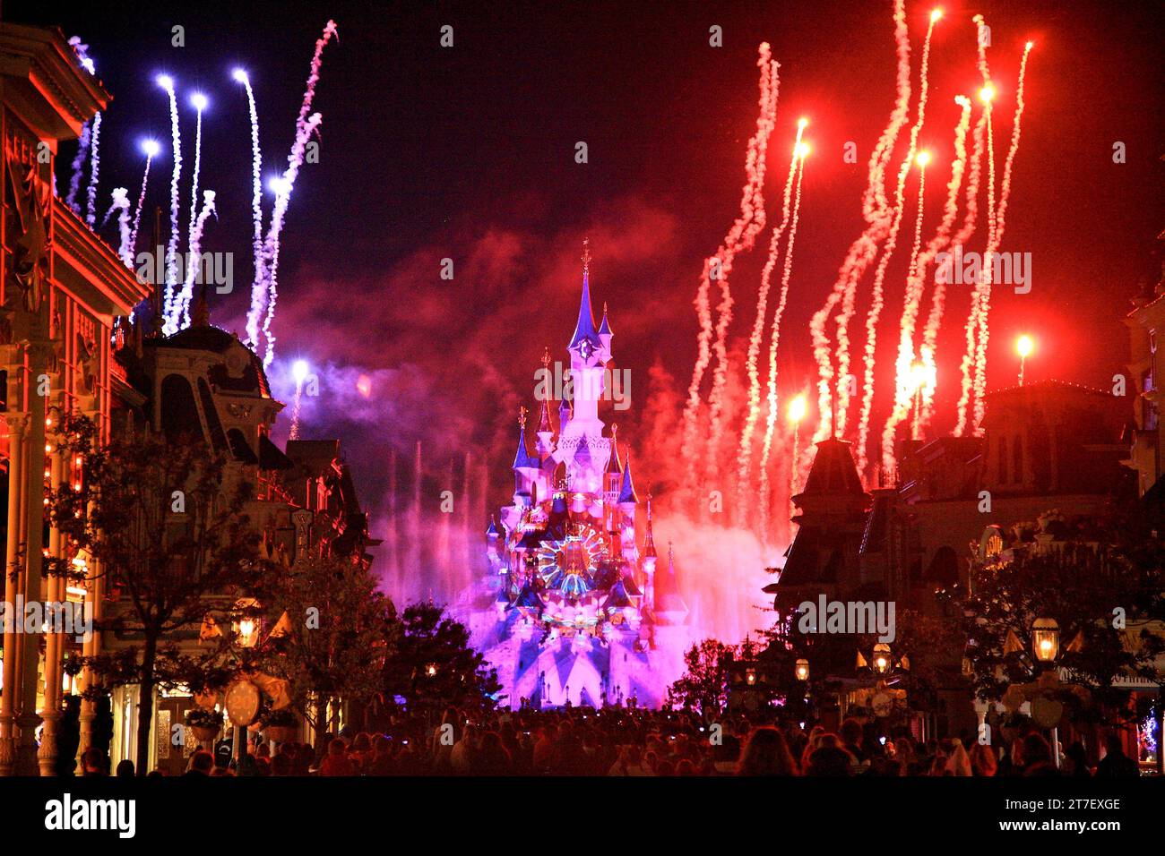 Rotes und violettes Feuerwerk beim Euro disney in paris mit Schloss und Zuschauermenge im Blick Stockfoto