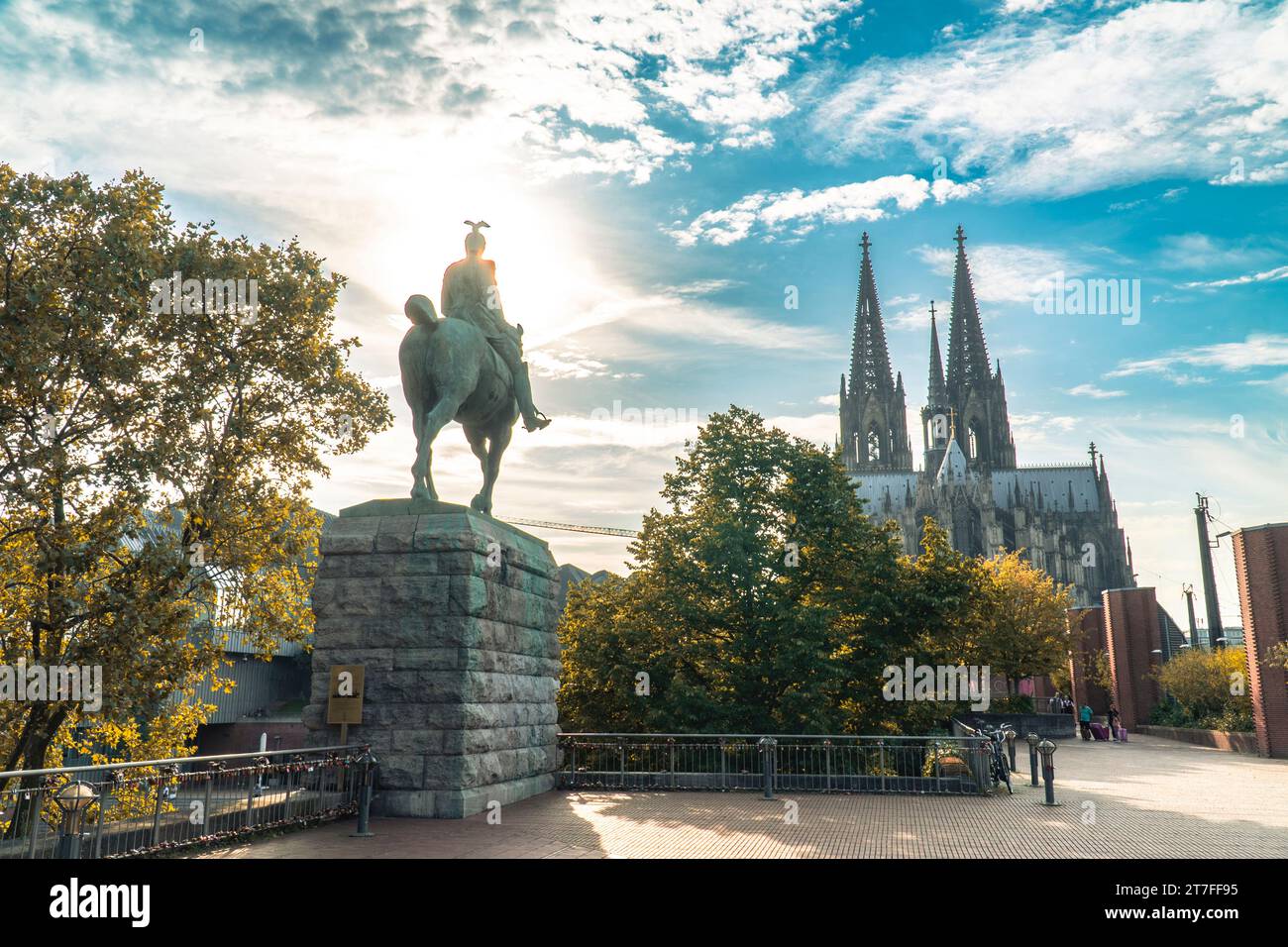 Blick auf den Kölner Dom und die Reiterstatue von Kaiser Wilhelm II. Vor dem Hintergrund der Sonne und des bewölkten Himmels Stockfoto