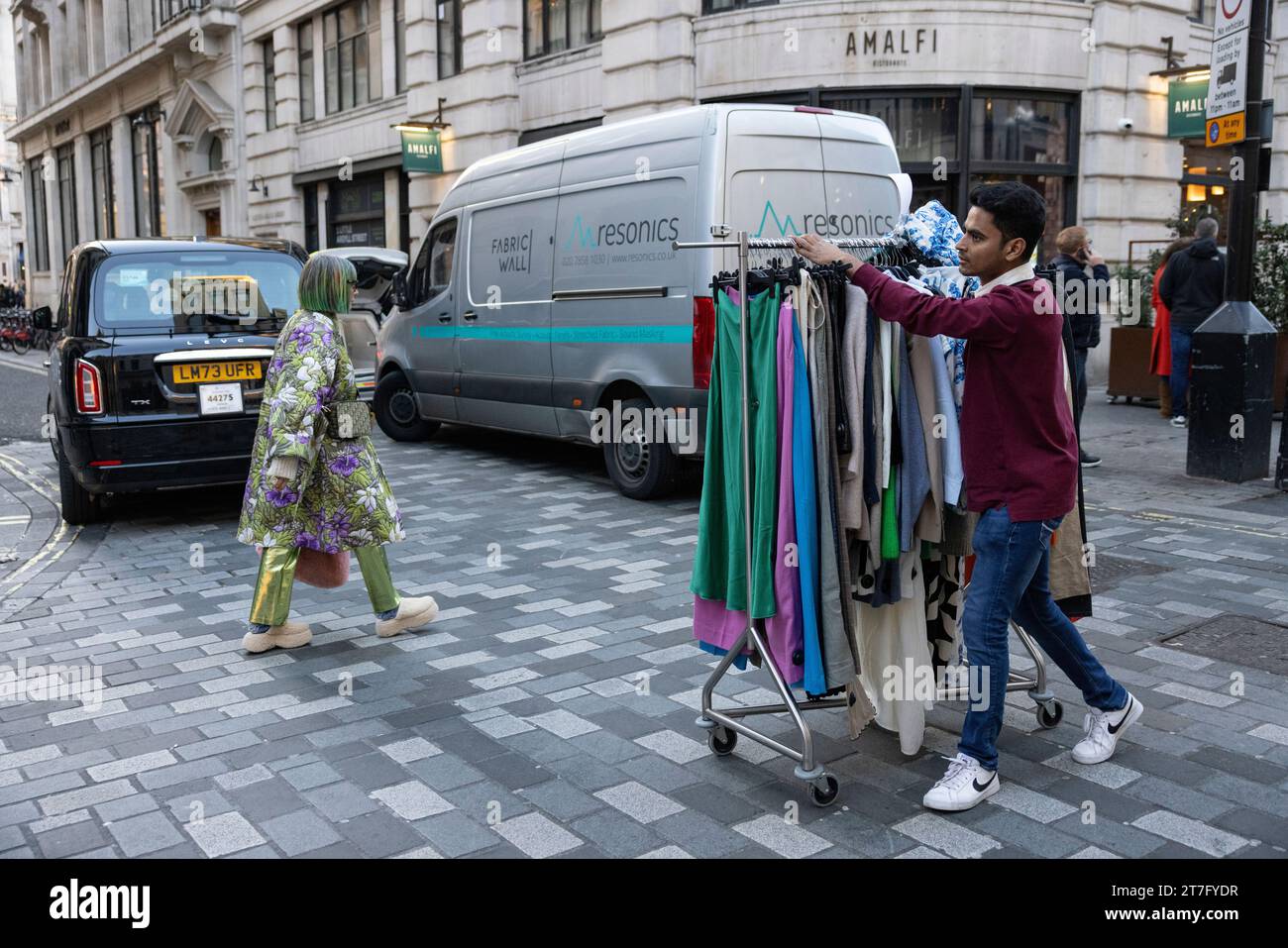 Der Modeassistent schiebt einen Kleiderwagen entlang der Straße im Londoner West End, England, Großbritannien Stockfoto