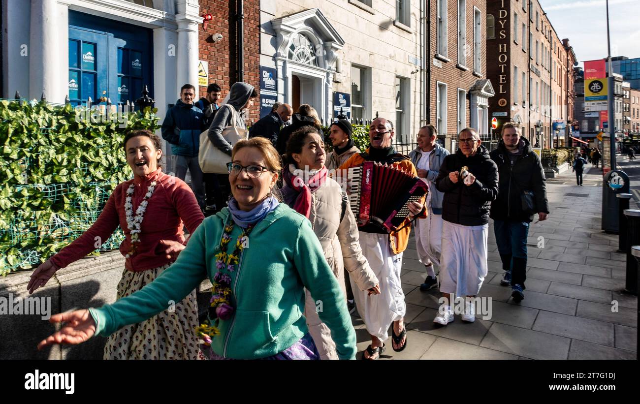 Fröhliche Straßenprozession mit Musik und Tanz von Hare Krishna-Anhängern an einem sonnigen Tag in Dublin, Irland, in der Nähe von Cassidy's Hotel und Parnell Square. Stockfoto