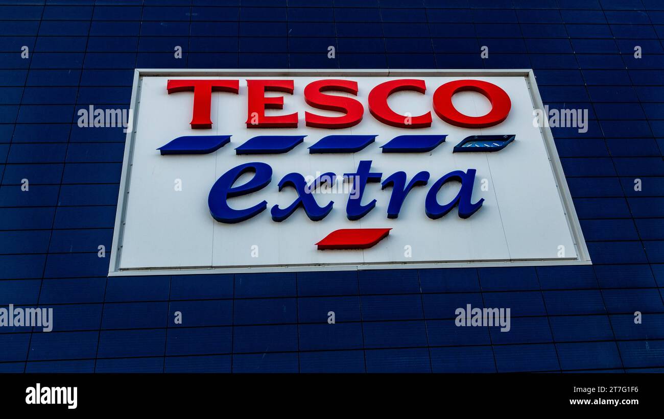 Tesco Extra Store-Schild an einer dunkelblauen gefliesten Wand mit auffälligem rot-blauem Branding auf weißem Hintergrund, das den britischen Supermarkt ch repräsentiert Stockfoto