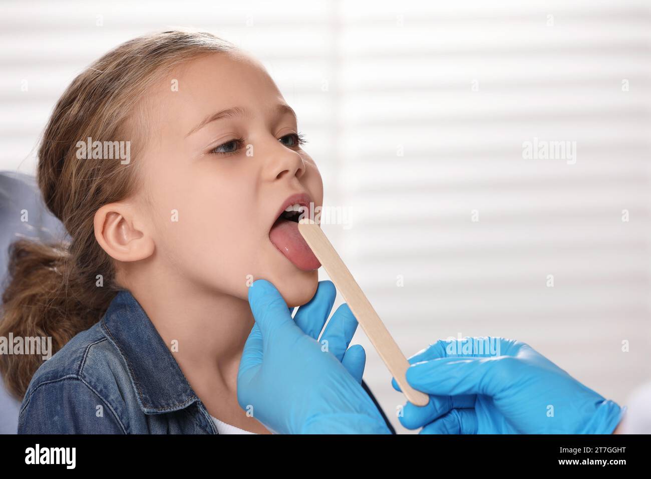 Arzt untersucht die Mundhöhle eines Mädchens mit Zungendepressor drinnen. Leerzeichen für Text Stockfoto