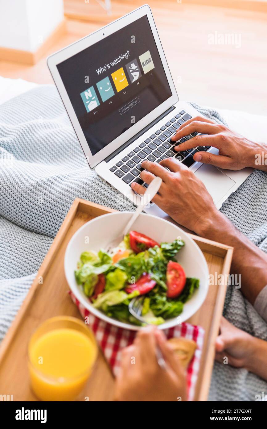Ein Paar isst Salat und stöbert auf der Website des Streaming-Service Stockfoto