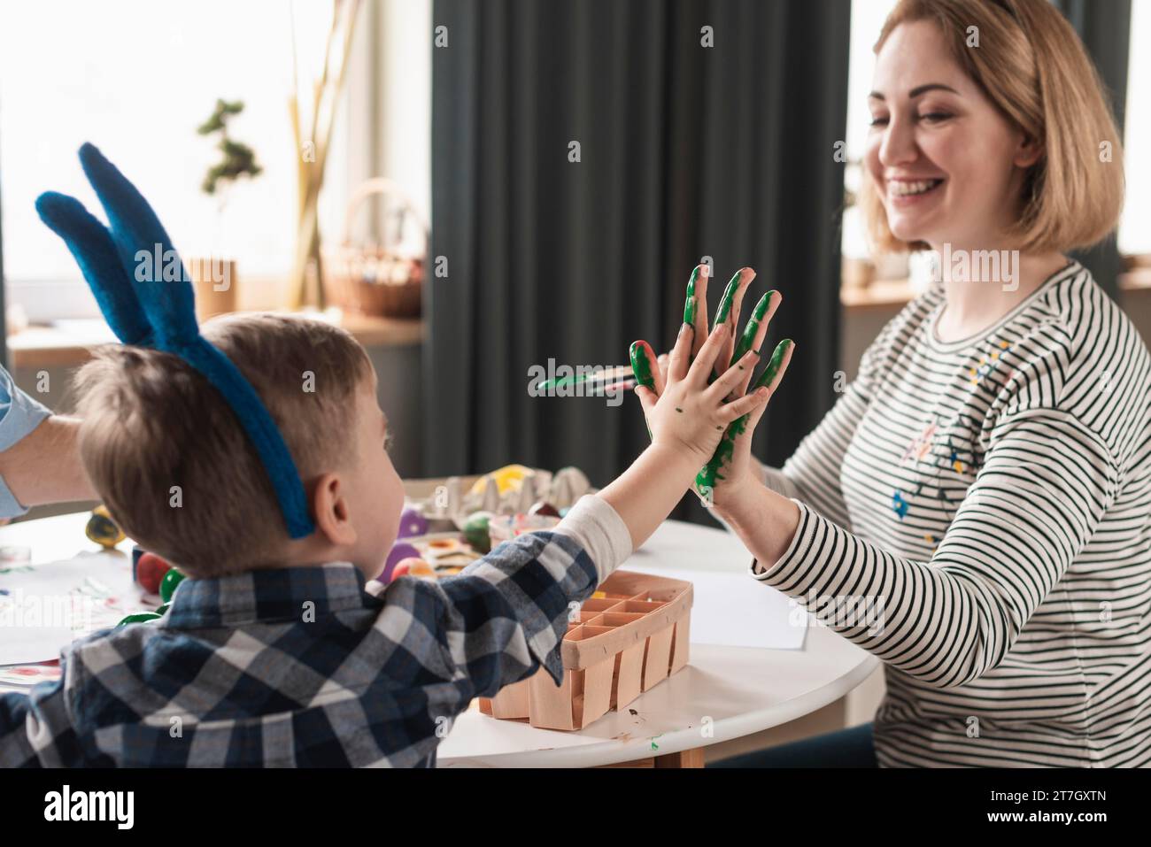 Glückliche Mutter, die Söhne anmalt, Hände ostern Stockfoto