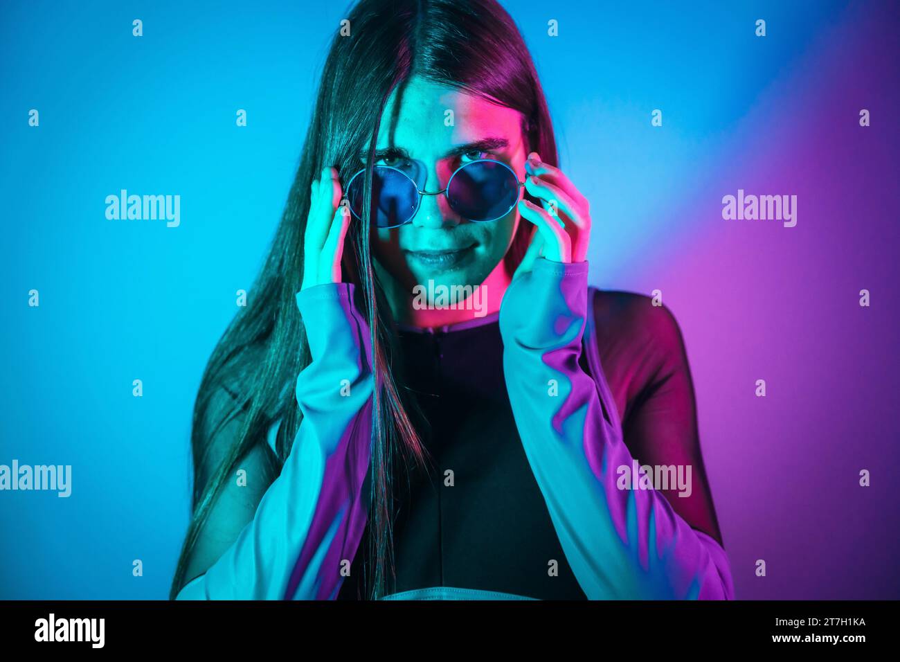 Futuristisches Studio-Porträt mit Neonlichtern von nicht binären Geschlechtern, die Sonnenbrillen tragen Stockfoto