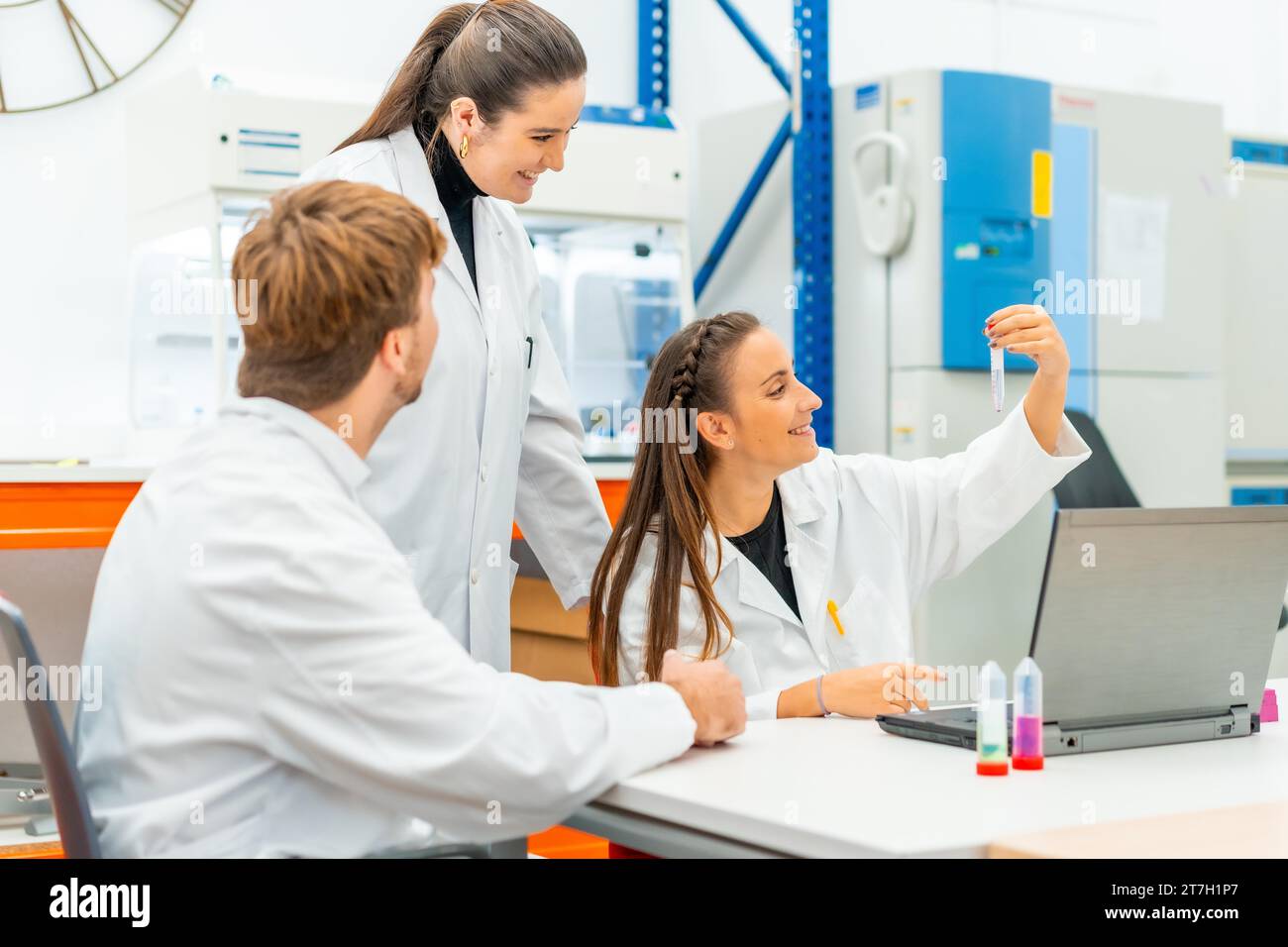 Wissenschaftler betrachten Proben, während sie mit einem Laptop arbeiten, der auf einem Tisch im Labor sitzt Stockfoto