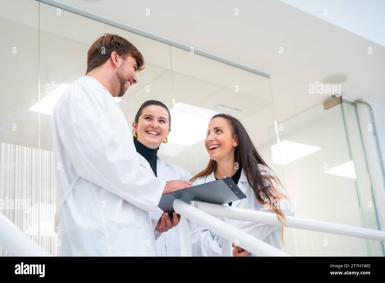 Tiefwinkelansicht dreier Nachwuchswissenschaftler, die in einem Labor Dokumente sprechen und lesen Stockfoto