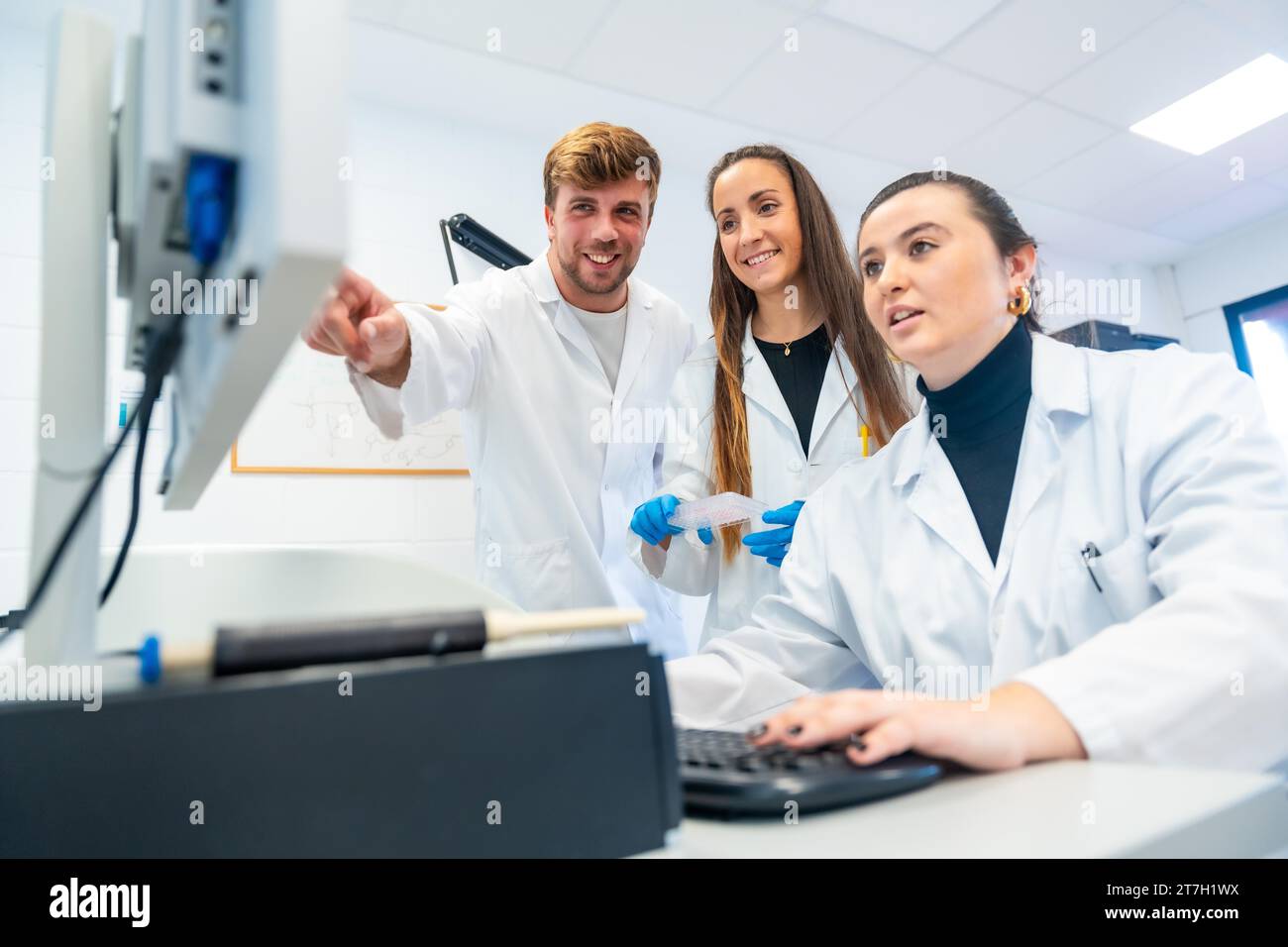 Glückliche Ärzte, die Computer benutzen und in einem Forschungslabor auf den Bildschirm zeigen Stockfoto