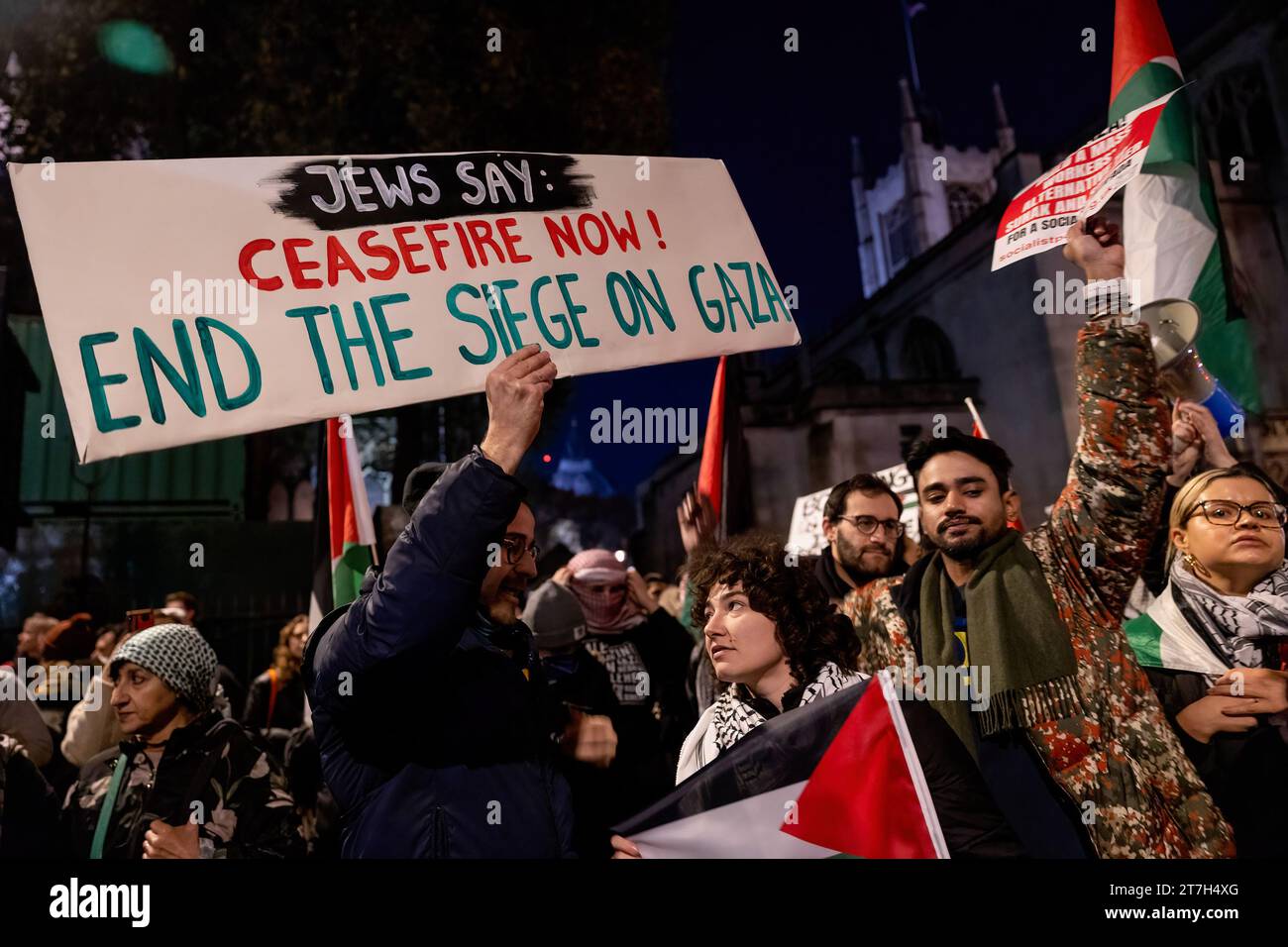 London, Großbritannien. November 2023. Ein Demonstrant hält ein Schild, während er vor dem britischen Parlament in Westminster demonstriert. Palästinensische Anhänger versammeln sich heute Abend vor dem Parlamentsplatz, während die Parlamentsabgeordneten über die Änderung des Waffenstillstands aus der Rede des Königs abstimmen, die von der Scottish National Party (SNP) vorgeschlagen wurde. Sie fordern einen sofortigen Waffenstillstand und die Eindämmung der Bombardements und der unschuldigen Tötung von Palästinensern, die von israelischen Truppen in Gaza gefangen sind. Quelle: SOPA Images Limited/Alamy Live News Stockfoto