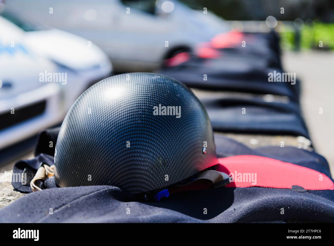 Schutzhelm mit Neoprenanzügen, die an einer Wand an einem Parkplatz an der Küste trocknen, nachdem Kinder in einer kontrollierten Umgebung an den Klippen gesprungen waren. Stockfoto