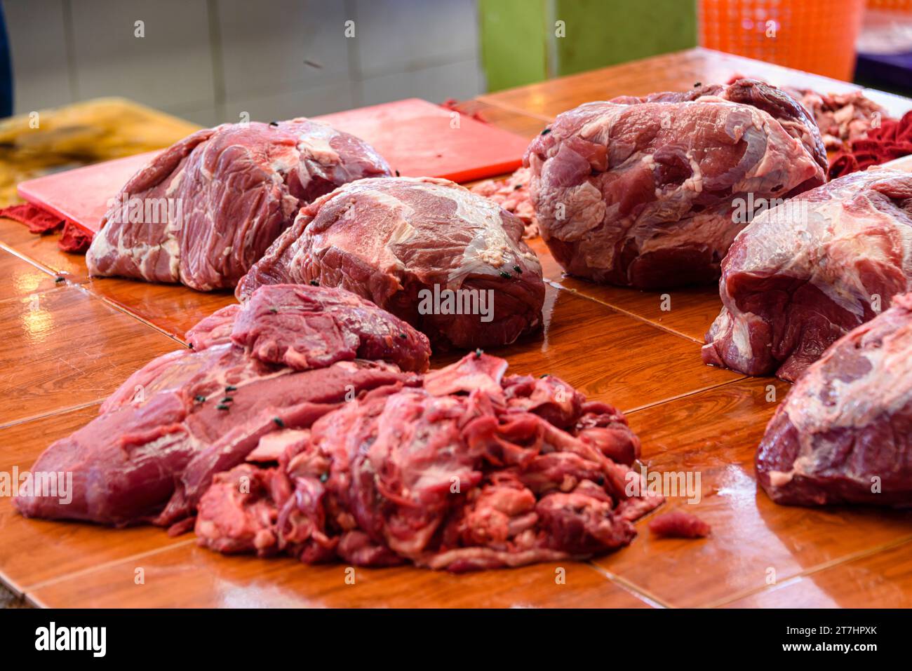 Fliegen landen auf Fleisch zum Verkauf an einem Metzgerstand auf dem traditionellen Mae Somchit Kata Frischmarkt, Kata, Phuket, Thailand Stockfoto