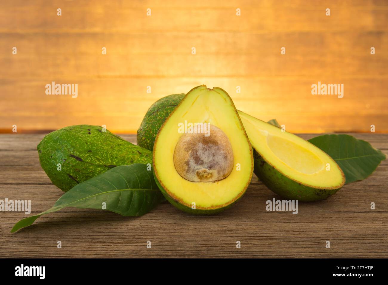 Frische Bio-Avocado und Avocadostücke auf einem alten Holztisch. Stockfoto